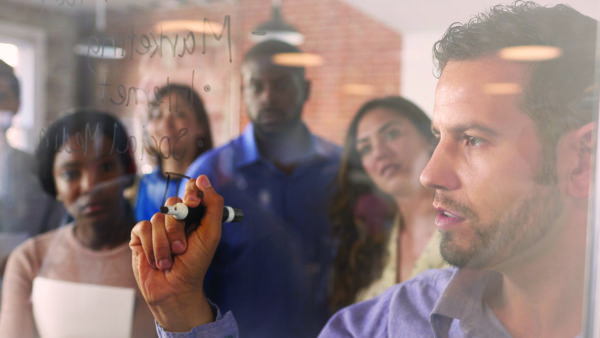 Businessman Writing Ideas On Glass Screen During Meeting